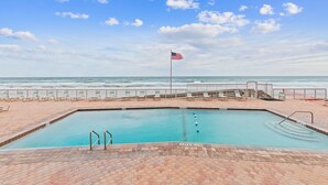 Ein Swimmingpool mit einer Flagge, Blick auf den Ozean und einer Terrasse aus Ziegelsteinen.