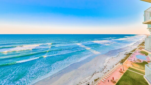 Een hotel aan het strand met een zwembad, een uitgestrekt strand en uitzicht op de oceaan.