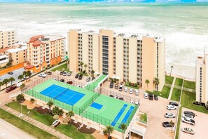 A high-rise hotel with a tennis court and parking area. - Oceanfront 10th-Floor Condo w/ Balcony, Pool, & Direct Beach Access (Daytona Beach Shores)