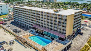 Ein mehrstöckiges Hotel mit Schwimmbad, Parkplatz und Blick auf die umliegende Landschaft.