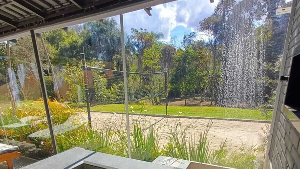 A hot tub with a view of a garden and a waterfall. - Cozy House "exclusively for Couples" Pet Friendly (Bragança Paulista)