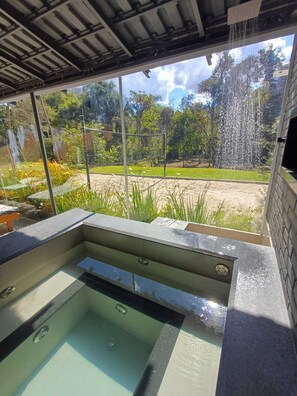 A hot tub with a view of a garden and a waterfall. - Cozy House "exclusively for Couples" Pet Friendly (Bragança Paulista)