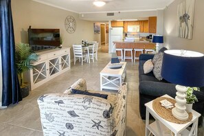 Un salon comprenant un canapé, un téléviseur et un coin repas avec des chaises et une table.