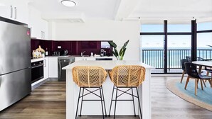 Una cocina moderna con una isla grande, electrodomésticos de acero inoxidable y vistas al mar a través de amplios ventanales.