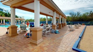 A covered outdoor area with a pool, lounge chairs, and a sandy area. - Oceanview Retreat w/ Balcony, Pool, & Steps from New Smyrna Beach (New Smyrna Beach)