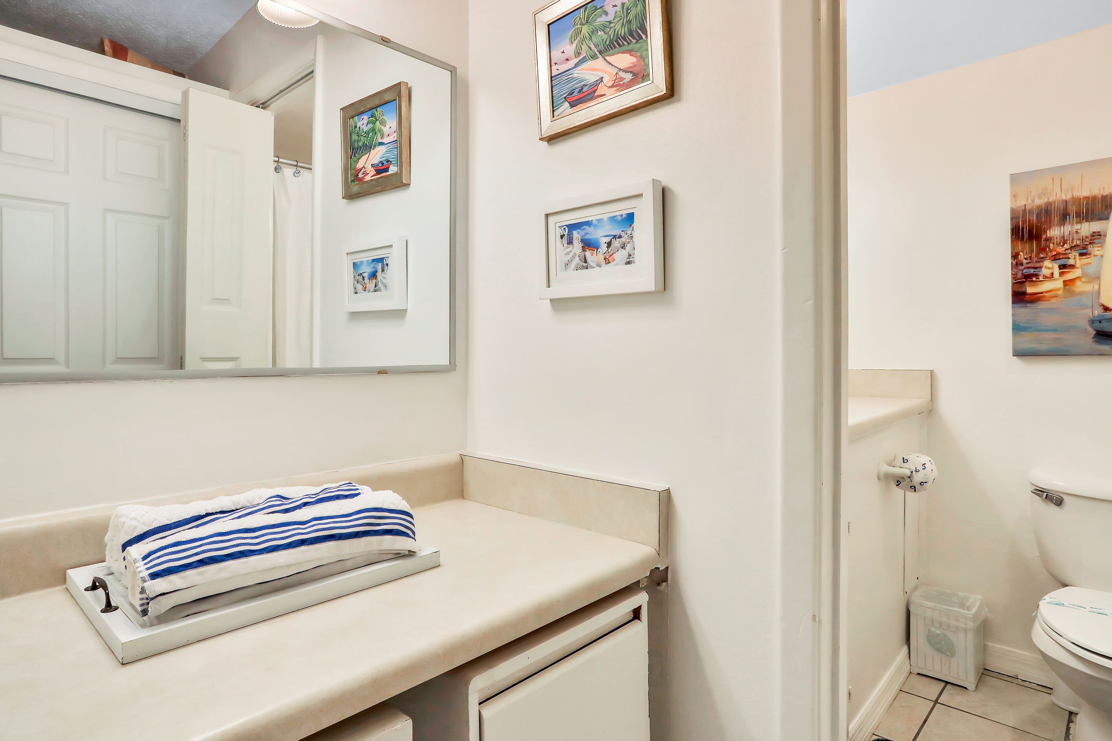 Een badkamer met een witte wasbak, een handdoek, fotolijstjes aan de muur en een toilet.