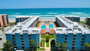 A hotel with two swimming pools, a beach view, and a parking lot. - Modern Coastal Condo w/ Balcony, Pool & Easy Walk to the Beach (New Smyrna Beach)