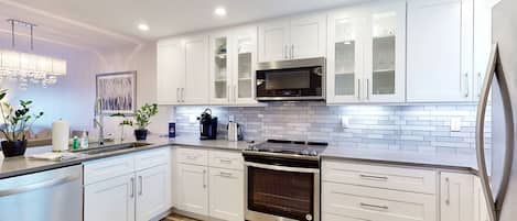 A modern kitchen with white cabinets, a stainless steel stove, and a microwave.