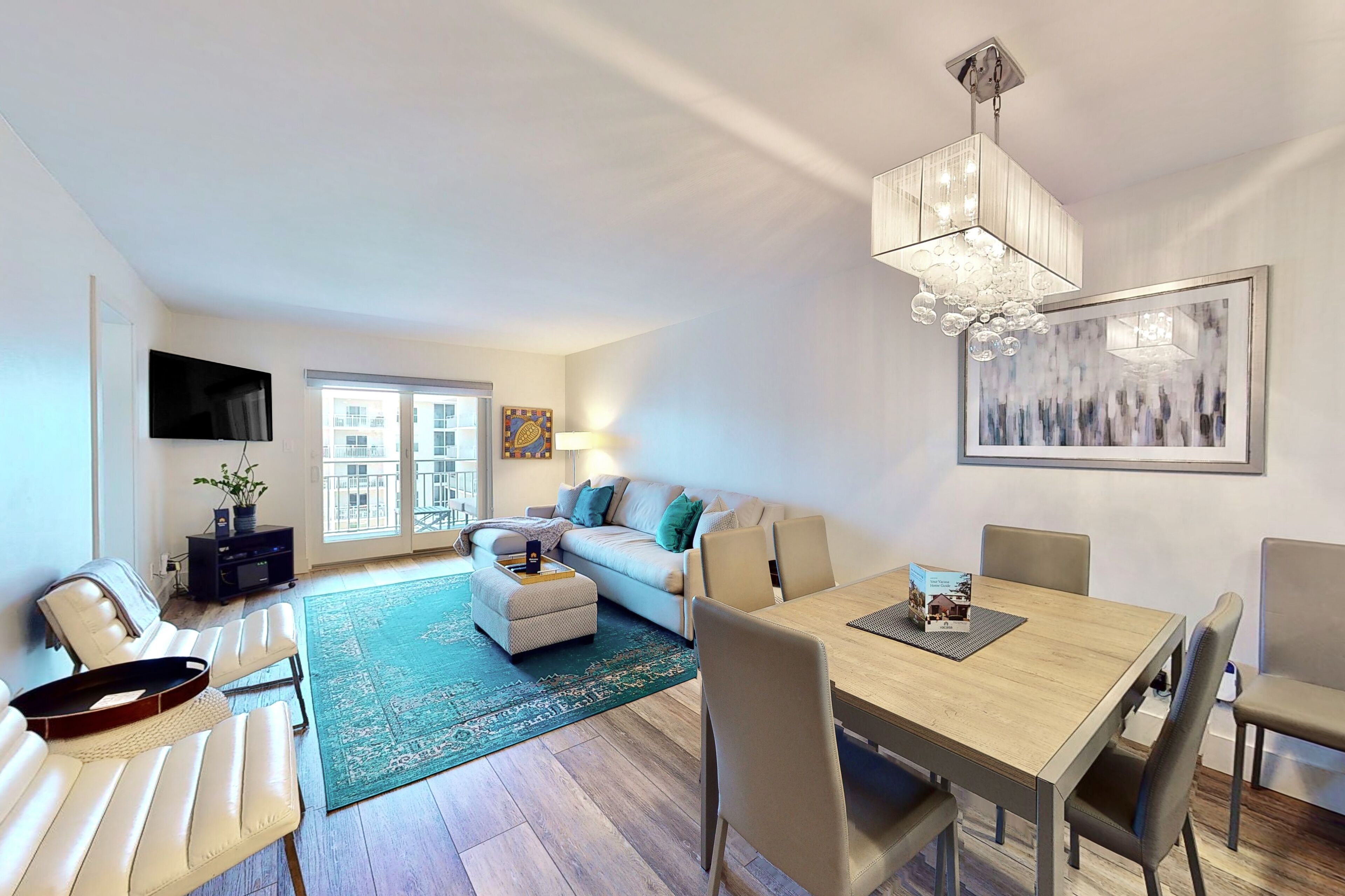 A modern living room with a sofa, a dining table, and a TV mounted on the wall.
