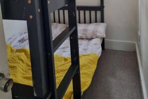 Een stapelbed met een gele deken en een houten hoofdbord.