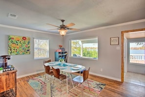 A dining area with a round table, chairs, a ceiling fan, and a view of the outdoors.