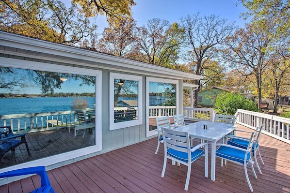 A covered deck with a table and chairs, overlooking a body of water.