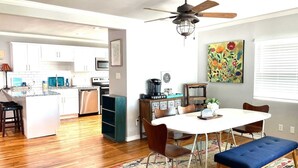 A modern kitchen with white cabinets, a dining area with a white table and chairs, and a ceiling fan. - Dock & Fire Pit: Lakefront Cedar Creek Home! (Mabank)