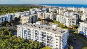 Ein hoch aufragendes Wohnhaus mit mehreren Balkonen, einem Innenhof und Blick auf das Meer.