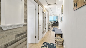 Un pasillo con paneles de madera, puertas blancas y vista a una sala de estar.
