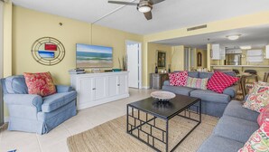 A living room with a ceiling fan, a sofa, a coffee table, and a painting on the wall.