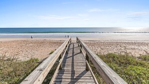 A wooden boardwalk leading to a beach with clear skies.