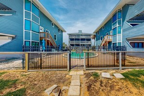 Une cour intérieure avec une fontaine centrale, entourée de bâtiments bleus dotés de balcons et d’une entrée fermée par un portail.