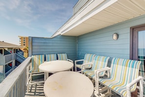Un balcon avec des coussins à rayures, une table ronde et une vue sur un bâtiment en arrière-plan.