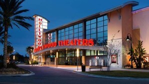 L’extérieur du Hollywood & Vine Hotel & Theater se distingue par une grande enseigne lumineuse portant le nom de l’hôtel, une façade moderne en verre et des palmiers au premier plan.