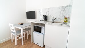 A compact kitchenette with a microwave, kettle, and sink. - Centra High Road (London)