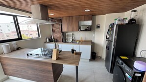 A modern kitchen with a wooden island, stainless steel appliances, and a view of the city. - Beautiful 2-bedroom apartment with terrace in Mexico City (Ciudad de México)