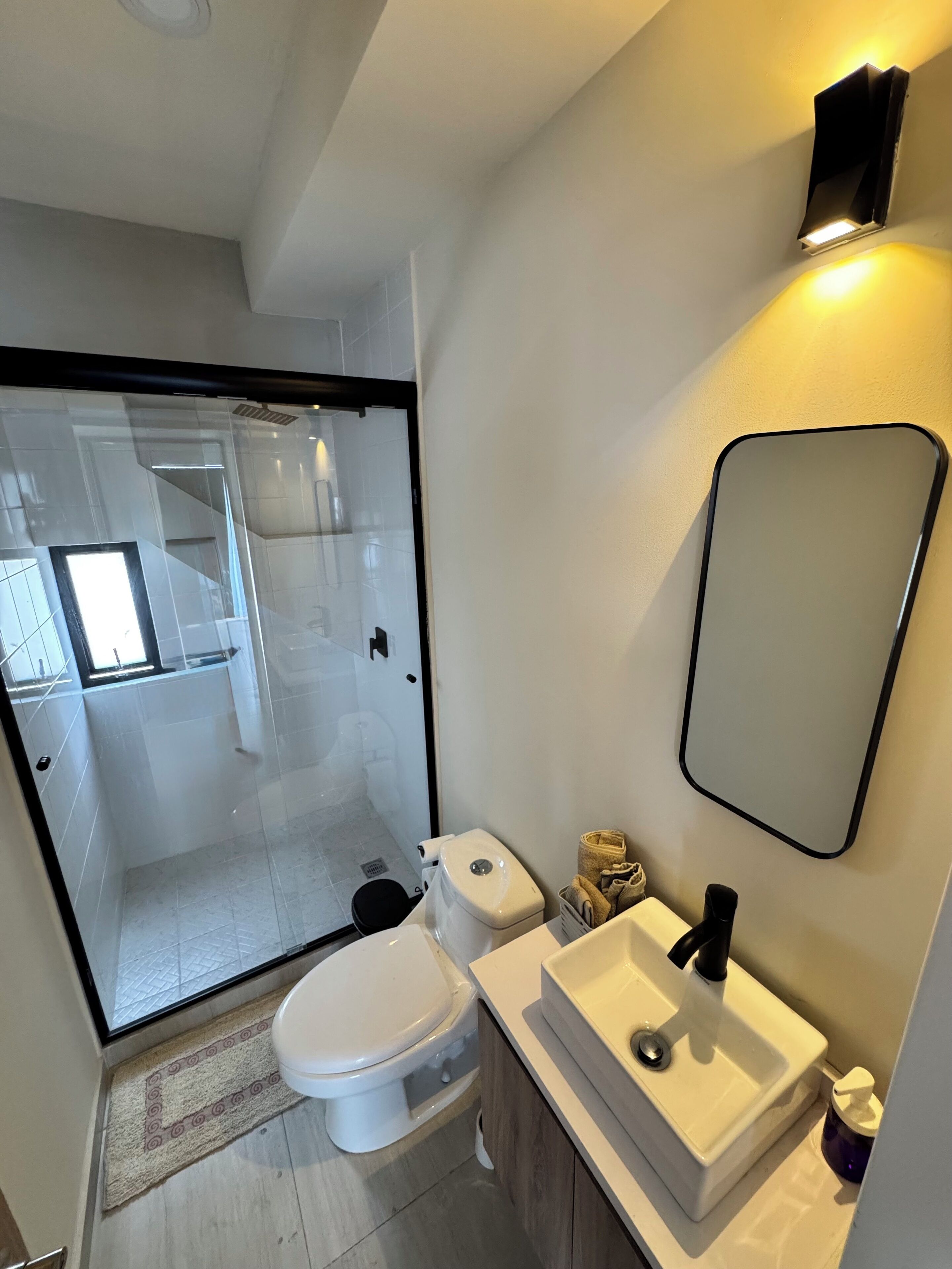 Een moderne badkamer met toilet, wastafel en douchecabine met glazen wanden.