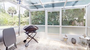 Un espacio de patio techado con una parrilla, una silla y faroles decorativos.