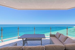 Un balcon avec une table et un canapé donnant sur une plage.