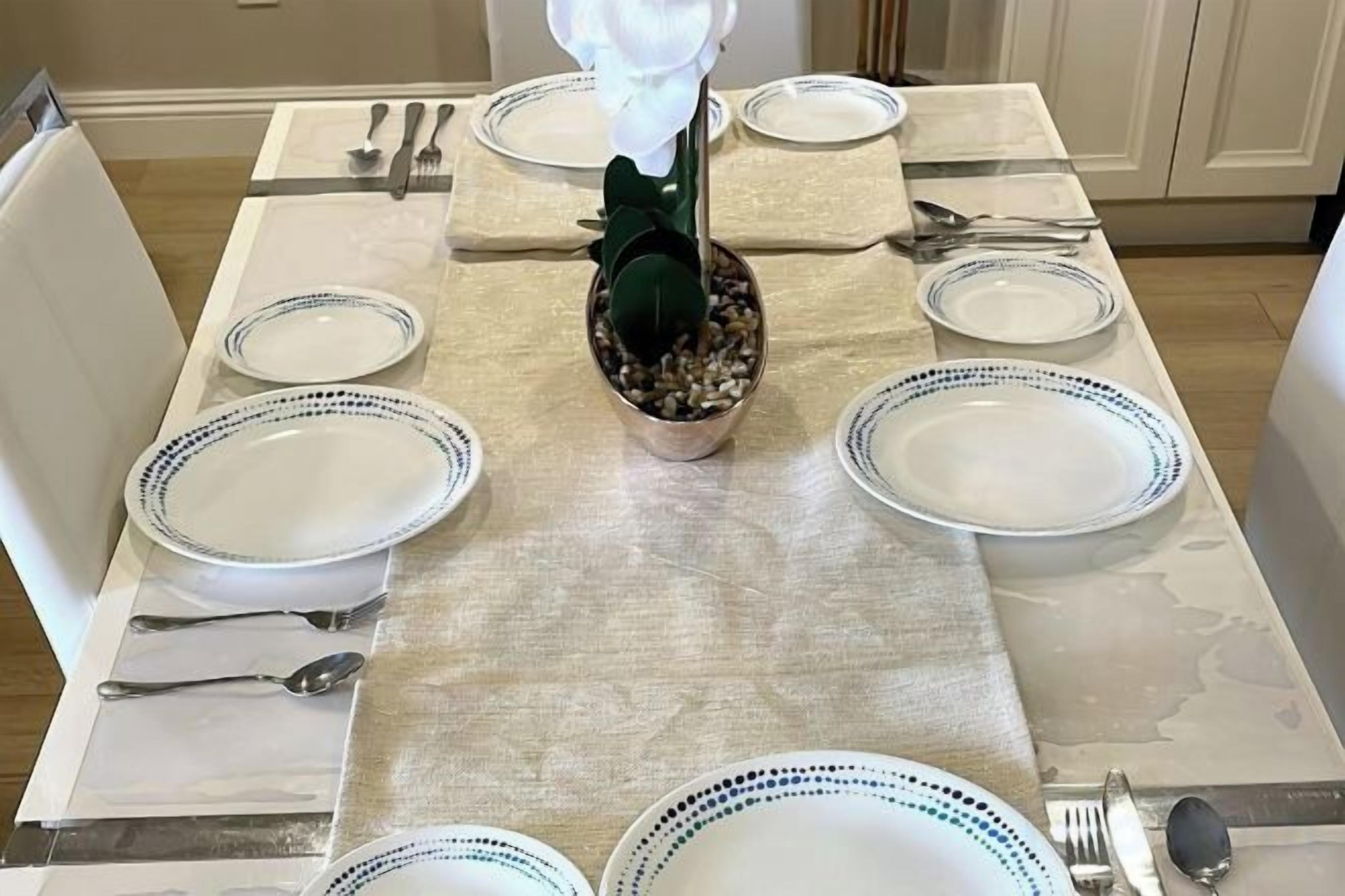 Une table à manger dressée avec des assiettes, des couverts et un centre de table.