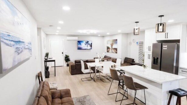 A modern kitchen with a central island, a dining area with a white table and chairs, and a living area with a brown sofa. - Exotic home 3bed2bath 20min to beach downtown (La Presa)