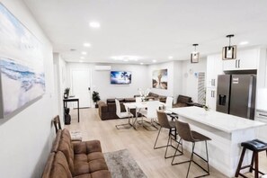 A modern kitchen with a central island, a dining area with a white table and chairs, and a living area with a brown sofa. - Exotic home 3bed2bath 20min to beach downtown (La Presa)