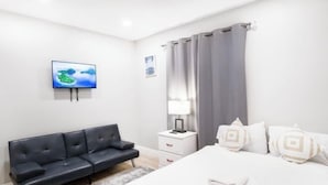A modern hotel room with a bed, a black sofa, a nightstand with a lamp, and a painting on the wall. - Exotic home 3bed2bath 20min to beach downtown (La Presa)