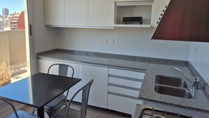 A modern kitchen with white cabinets, a granite countertop, a built-in stove, and a window overlooking a cityscape. - Excellent apartment in building with amenities. In front of Abasto Shopping Mall (Buenos Aires)