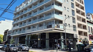 A multi-story building with balconies, a ground-level entrance, and several parked cars. - Excellent apartment in building with amenities. In front of Abasto Shopping Mall (Buenos Aires)