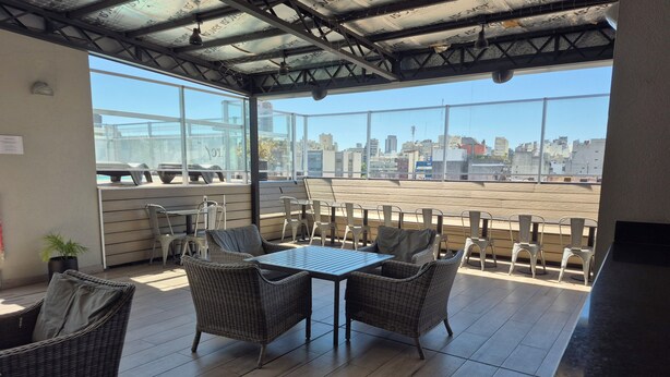 A rooftop terrace with wicker furniture, a table, and a view of the cityscape. - Excellent apartment in building with amenities. In front of Abasto Shopping Mall (Buenos Aires)