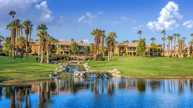 Ein Resort mit mehreren Villen, einem zentralen Wasserspiel und Palmen.