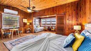 A wooden-paneled room with a bed, a desk, and a chair. There is a window with blinds, a ceiling fan, and a lamp. - Gulf View Escape on the Beach with Lounging Deck (Englewood)
