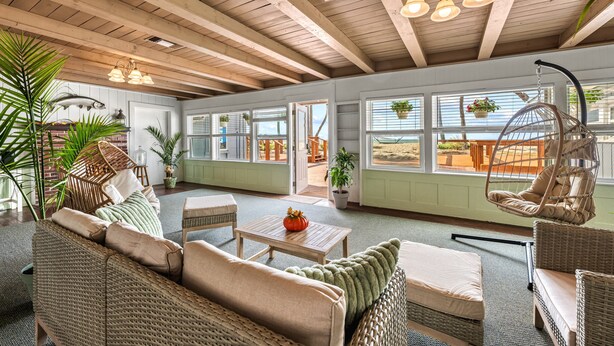 A spacious room with high ceilings, wicker furniture, and large windows allowing natural light. - Gulf View Escape on the Beach at Resort with Pool, Kayaks, and More! (Englewood)