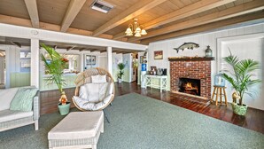 A spacious living room with a fireplace, wooden ceiling beams, and a large window. - Gulf View Escape on the Beach at Resort with Pool, Kayaks, and More! (Englewood)