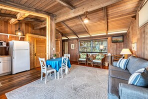 A cozy cabin interior with a dining area, kitchen, and seating space. - Beach Front Escape with Private Balcony & Beach Access, Pet Friendly (Englewood)