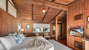 A wooden-paneled room with a bed, a television, and a window with blinds. - Beach Front Escape with Private Balcony & Beach Access, Pet Friendly (Englewood)