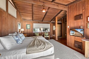 A wooden-paneled room with a bed, a television, and a window with blinds. - Beach Front Escape with Private Balcony & Beach Access, Pet Friendly (Englewood)
