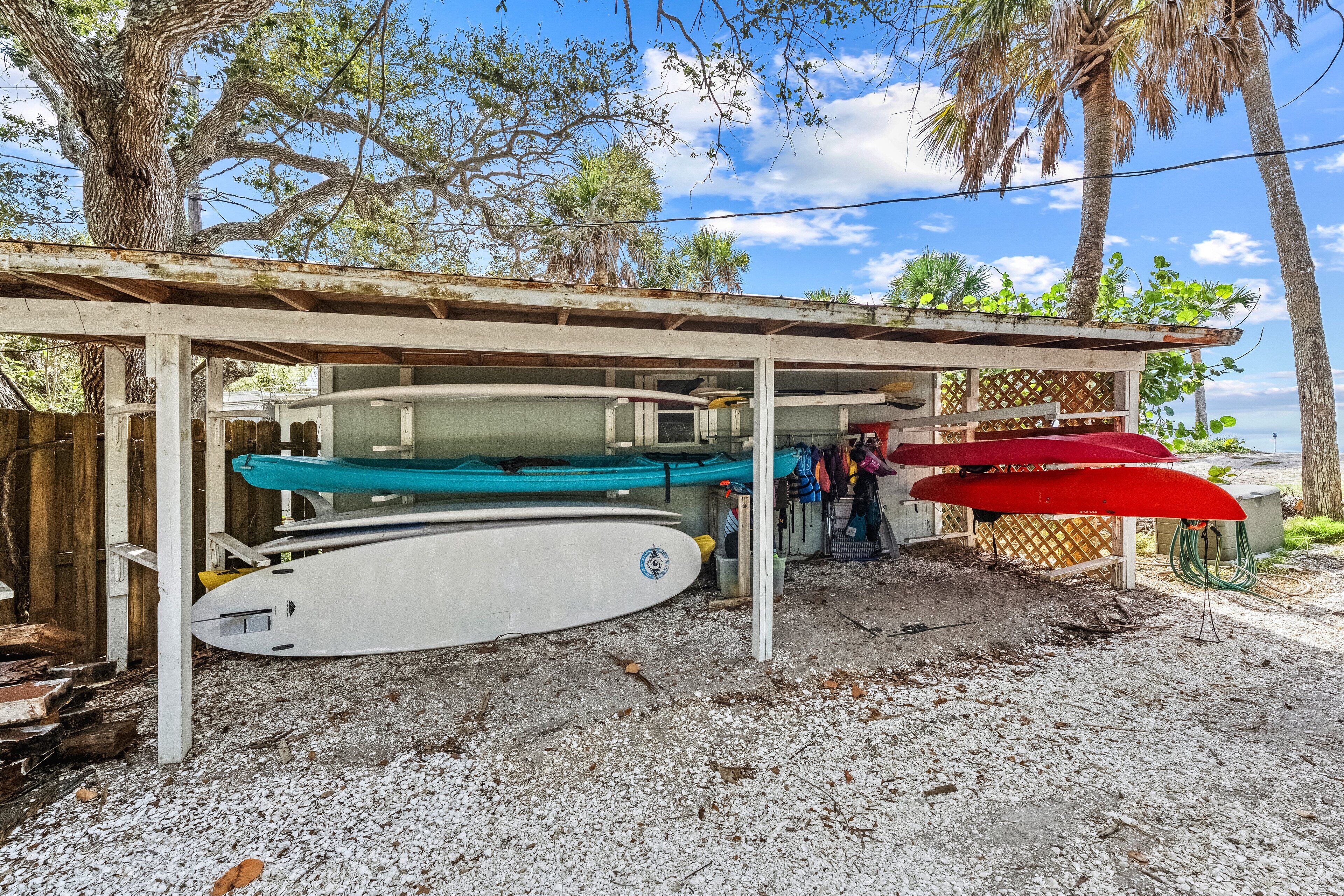 A covered area with surfboards and a red umbrella.