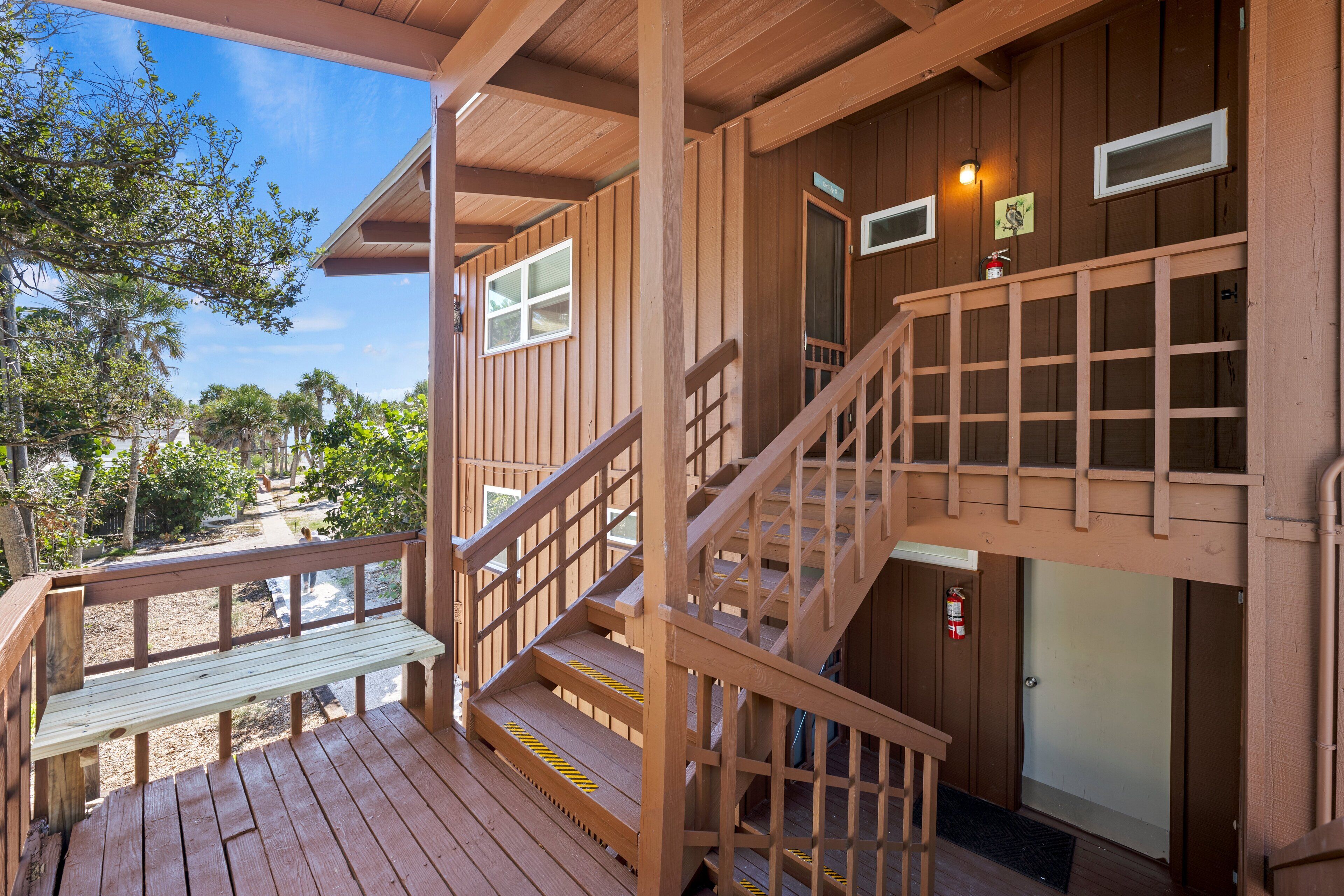 Una terraza de madera con un banco y una escalera que conduce a un nivel superior.