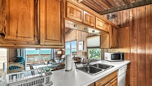 Una cocina con armarios de madera, encimera blanca, un lavabo, un microondas y un lavavajillas.