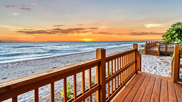 A wooden deck leading to a beach with a sunset view. - Gulf Front Escape on the Beach with Shared Viewing Deck & Pool - Cozy & Intimate (Englewood)