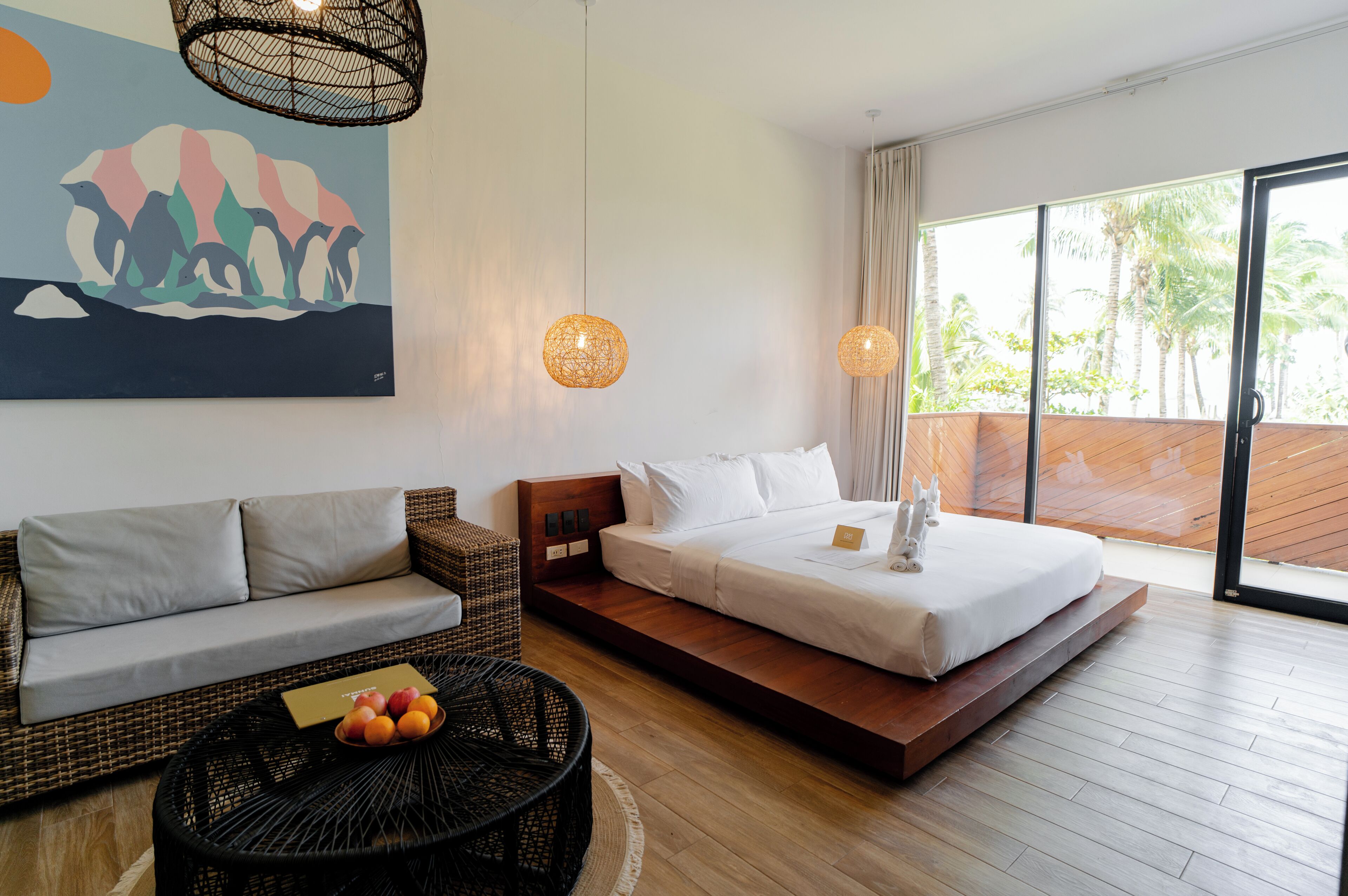 A modern bedroom with a bed, sofa, and wicker coffee table.