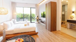 Habitación de hotel moderna con una cama grande, televisión, armario de madera y vistas a zonas verdes.
