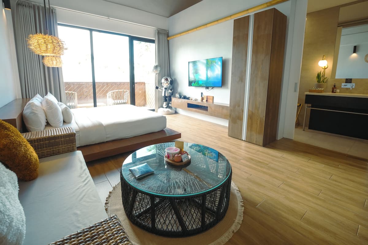 Un salon moderne avec un canapé, une table basse ronde en verre, un téléviseur et un balcon offrant une vue dégagée.